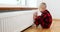 Boy warm one\'s hands near radiator at home.