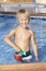 Boy with watering can in the swimming pool