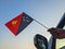 Boy waving Papua New Guinea flag against the blue sky from the car window close-up shot. Man hand holding Papuan flag