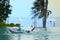 Boy wear goggles on floater in swimming pool with water splash on blur beach background