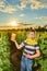 A boy wearing a beekeeper mask holds a jar of honey in the middle of a sunflower field and imagines how he eats honey