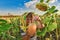 A boy wearing a beekeeper mask holds a jar of honey among a sunflower field