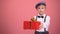 Boy wearing bow tie and suspenders showing gift box to camera, holiday present