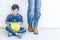 Boy wearing construction work protection wear sitting beside his father feet