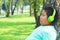 A boy wearing a green music earphone standing against a tree