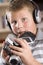 Boy wearing headphones holding many electronics