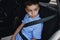 A boy wearing seat belts travels in a protective child car seat. Traveling safely with children