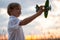 Boy in a  white shirt with a plane in hands against sky. Kid holds a wooden airplane and dreams of being a pilot, on the nature.