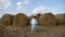 Boy in a white shirt and a straw hat is barefoot on a sloping field