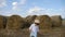 Boy in a white shirt and a straw hat is barefoot on a sloping field