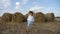 Boy in a white shirt and a straw hat is barefoot on a sloping field