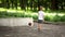 A boy in a white T-shirt in the park kicks a ball against the wall
