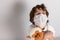 Boy in white tshirt and protective medical mask closed his eyes and afraid with toys monkey on white background. Fight with