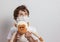 Boy in white tshirt and protective medical mask looking up with toys monkey on white background. Fight with Coronavirus epidemic