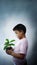 The boy who is holding a pot of seedlings