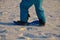 Boy in winter blue jumpsuit tries to ride a children`s plastic snowboard. tests stability and holds on to the string.