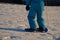 Boy in winter blue jumpsuit tries to ride a children`s plastic snowboard. tests stability and holds on to the string.