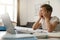 A boy yawning and rubbing his eyes while he is doing homework at home. Child education concept