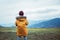 Boy in yellow coat looks on evening autumn mountain valley panorame