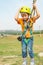 A boy in a yellow helmet holds on to the rope and looks into the camera on the cable car in an extreme park.