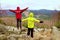 Boy in yellow and man in red warm jacket stand on a rock in a cold windy spring day. Active lifestyle, outdoor activities