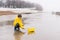 A boy in a yellow raincoat looks at the water surface lake, sea, river, ocean.