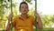 A boy in a yellow shirt riding on a swing.