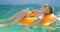 A boy in yellow sunglasses lounges in pool on inflatable ring