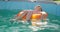 A boy in yellow sunglasses lounges in pool on inflatable ring