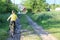 A boy in a yellow T-shirt rides a yellow bike. Picture from the back.