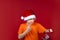 A boy in a yellow T-shirt and a Santa Claus hat holds a gift bag in his hand and shakes his fist at it