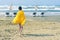 A boy in a yellow towel walks on the sandy Mackenzie beach in Larnaca in the autumn windy weather. Cyprus.