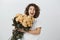 Boyfriend decided to surprise girlfriend with present. Good-looking amazed curly-haired female holding bucket of roses