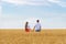 Boyfriend and girlfriend holding hands on background of Golden wheat and blue sky