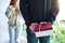 Boyfriend holding a gift box behind his back to surprising girlfriend