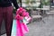 Boyfriend waiting for his girlfriend near cafe and holding flowers bouquet and bunch of pink gift bags. Ready for birthday party