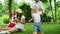 Boys and girl playing in forest. Laughing parents relaxing with children in park