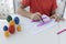 Boys hands painting handmade pink bunny ears, colorful eggs are near on table