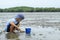 Boys looking for Snail shells on the sea floor mud.