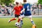 Boys play soccer game. Junior competition between players running and kicking soccer ball