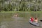 Boys row canoes across a lake