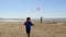 Boys running with kites at beach.