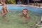 Boys swim in a frame pool on swimming circles. Smiling boy playing and having fun in the kids pool on a sunny summer day