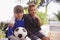 Boys will be boys. two young boys sitting outside with a soccer ball.