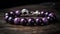 a bracelet with purple beads and a silver bead on a wooden surface with a metal clasp on the end of the bracelet and a black bead