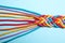 Braided colorful ropes on light blue background. Unity concept