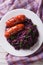 Braised red cabbage with sausage close-up on a plate. vertical t
