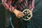 Brake disc on a bicycle wheel close-up. A bicycle mechanic in a fashionable plaid shirt holds a wheel in his hands. Bicycle repair