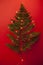 Branch of a forest fern decorated with lighted garland on a bright red background as a alternative christmas tree