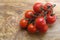 Branch of fresh cherry tomatoes on wood